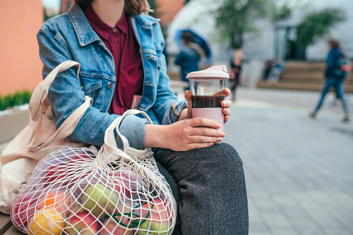 Mujer joven con taza de café reutilizable ecológica y bolsa de algodón, concepto de cero residuos photo