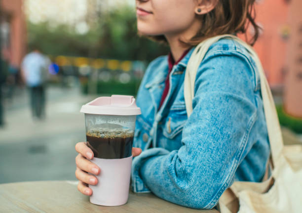 Young woman with eco-friendly reusable coffee cup and cotton bag, zero waste concept