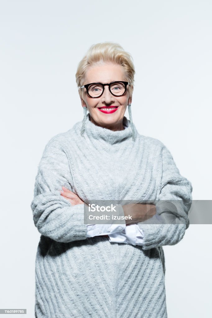 Portrait of beautiful senior woman in a sweater Portrait of beautiful senior woman in sweater standing with her arms crossed on white background Mature Adult Stock Photo