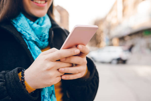 istock Young woman using phone on a city street 1160192065