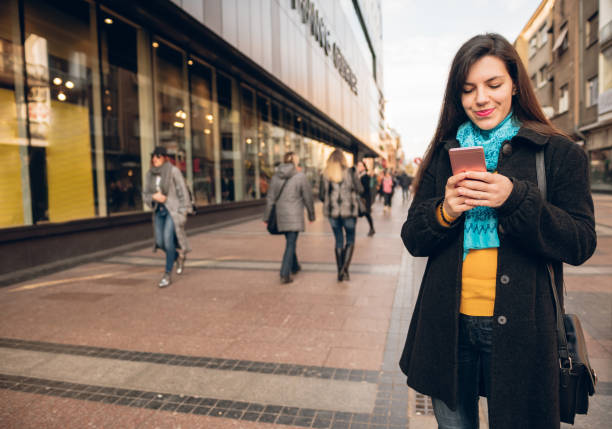 istock Young woman using phone on a city street 1160192126