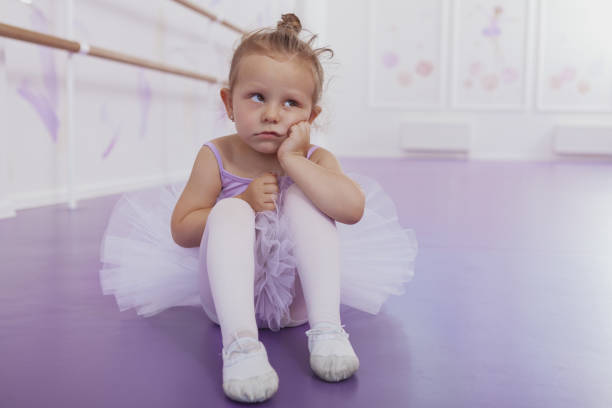 Cute little funny ballerina girl looking away with annoyed expression, copy space. Adorable little ballerina looking tired and bored at ballet class. Unhappy, angry child concept