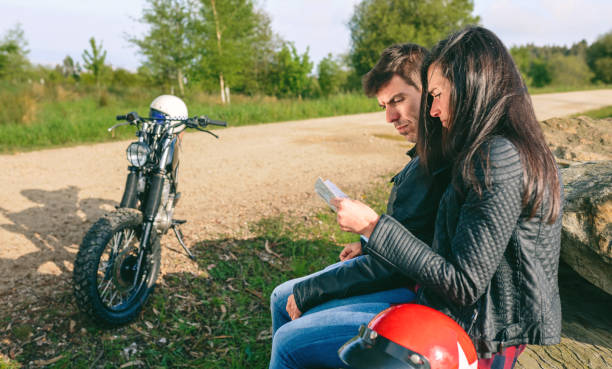 istock Lost couple sitting looking at a map with motorcycle 1160200129