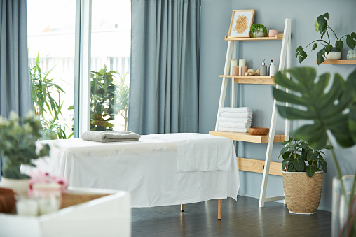 Shot of a tranquil massage room with plant life and a massage bed during the day