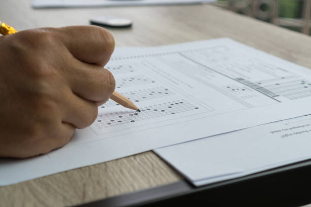 istock Exams test student in high school, university students holding pencil for testing exam writing answer sheet and exercise for taking in assessment paper on wood table classroom. Education study Concept 1160202365
