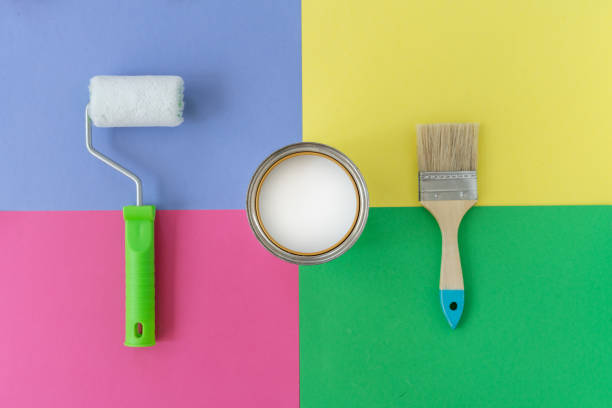 istock Brush with wooden handle, roller and open can with white paint on colorful background. Renovation concept. Place for text. 1160207851