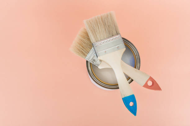 istock Brush with wooden handle on open cans on orange pastel background. Renovation concept. Place for text. 1160207903