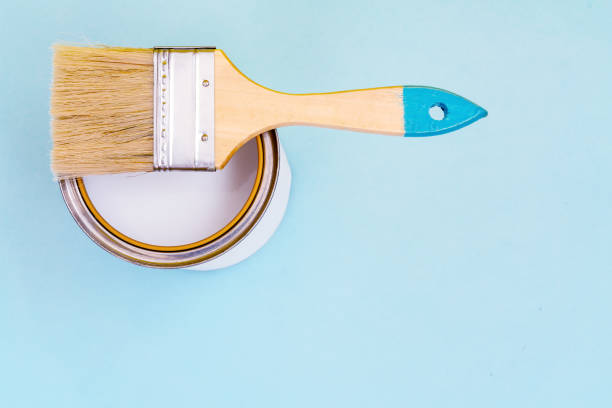 istock Brush with wooden handle on open cans on blue pastel background. Renovation concept. Place for text. 1160207972