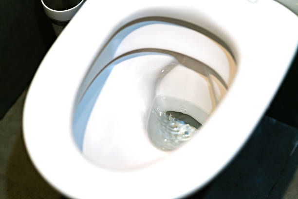 istock Toilet bowl flushing water in bathroom close up. 1160208048