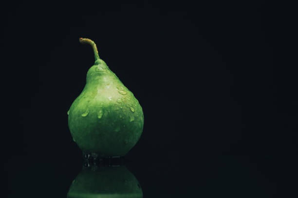 A green bottle of water is sitting on a table. The bottle is almost empty, with only a small amount of water left inside. The bottle is sitting on a green surface