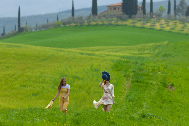 Two happy women walking on a bright green meadow. Mid shot