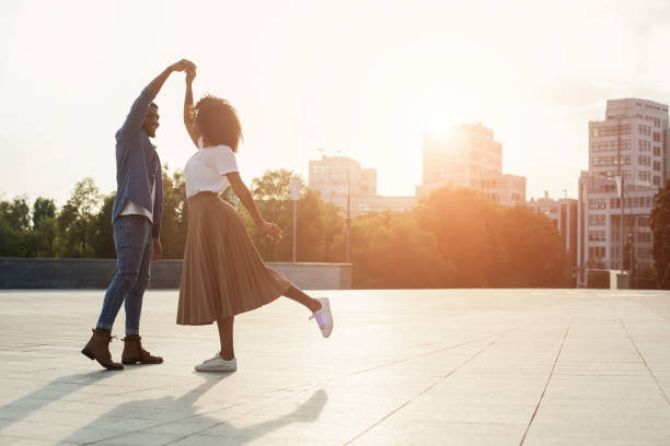 coppia amorevole che balla al tramonto per strada - flirting love togetherness heterosexual couple foto e immagini stock