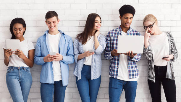 étudiants avec divers gadgets contre le mur blanc - group of people child teenager multi ethnic group photos et images de collection