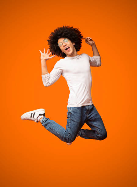 istock Ecstatic and amazed black guy jumping on orange background 1160220570