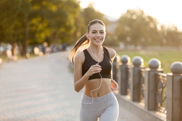 felice ragazza millenaria che corre in banchina e ascolta musica - fitness goal foto e immagini stock