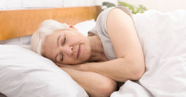 senior woman sleeping in bed in morning - sensuality lifestyles cheerful comfortable imagens e fotografias de stock