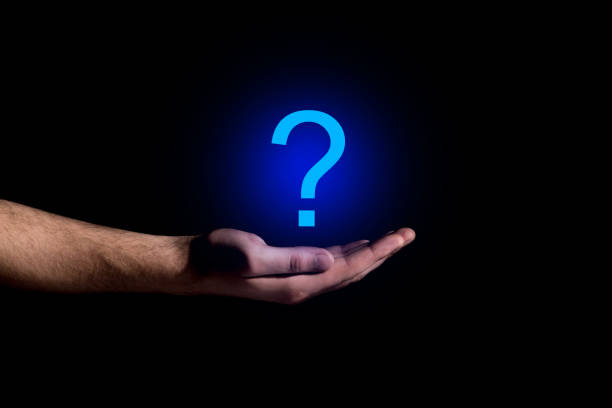 Hand showing a question mark in darkness stock photo