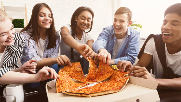 time for snack. happy students eating pizza and chatting - eating people group of people home interior imagens e fotografias de stock