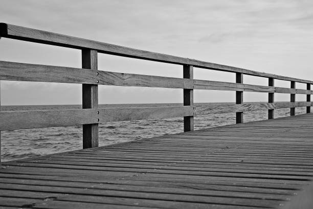 крупным планом деревянного моста через океан черно-белый - sea black and white horizontal horizon over water стоковые фото и изображения