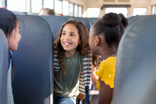 istock Smiling girl talks with friends on school bus 1160223213