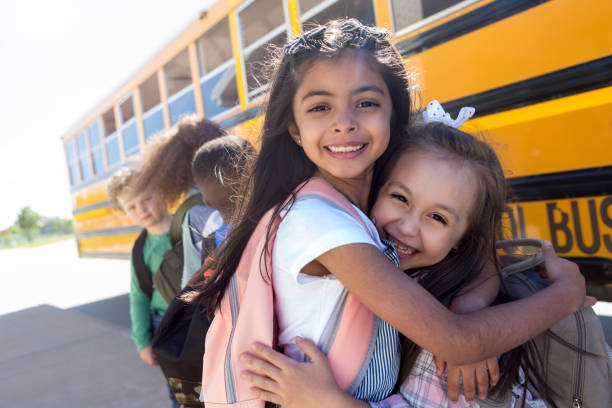 버스를 위해 줄을 서있는 동안 초등학교 소녀 포옹 - back to school child first day of school school bus 뉴스 사진 이미지