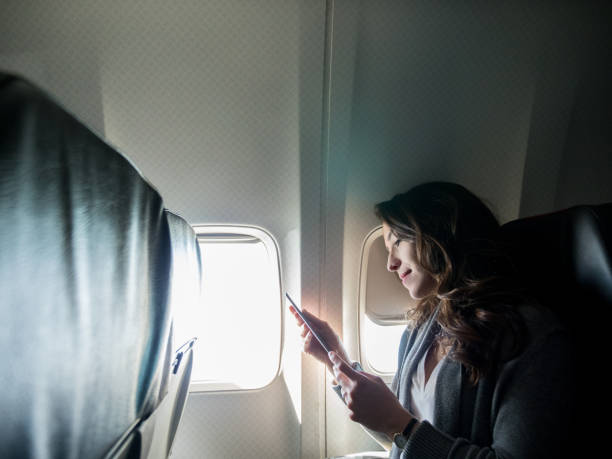 istock Young woman reads book on smart phone during flight 1160223634