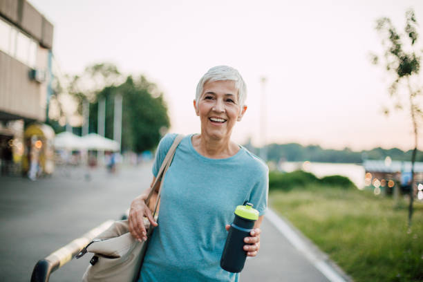 Happy woman with a bottle of water Smiling old woman standing in the city and holding handbag and a bottle of water older woman purse stock pictures, royalty-free photos & images