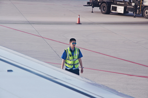 A Chinese ground engineering crew manager inspecting the tarmac of Beijing Capital International Airport (IATA: PEK, ICAO: ZBAA), Chaoyang–Shunyi, China
