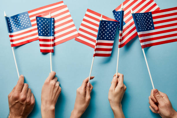 istock partial view of people holding american flags on blue background 1160231396