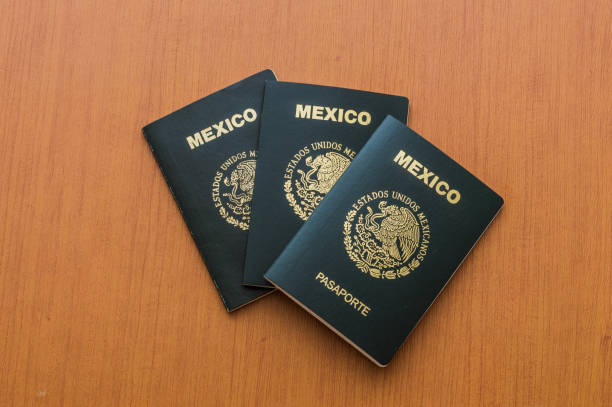 istock Three Mexican passports stacked on a wooden table. View from above. 1160232270