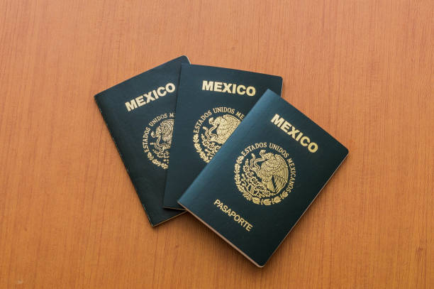 istock Three Mexican passports stacked on a wooden table. View from above. 1160232273