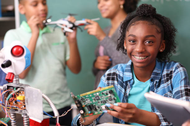 Junior high school age school students build robot in technology, engineering class. Junior high school age, African American teenage girl works on building a robot in technology class in school classroom setting.  STEM topics. high school high school student science multi ethnic group stock pictures, royalty-free photos & images