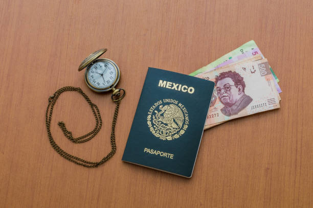 Pocket watch next to the Mexican passport. A package of five hundred Mexican pesos bills arranged like a fan on a wooden table. Mexican cash pesos. Concept of travel and tourism. Pocket watch next to the Mexican passport. A package of five hundred Mexican pesos bills arranged like a fan on a wooden table. Mexican pesos in cash. Concept of travel and tourism. dollar bill eagle stock pictures, royalty-free photos & images