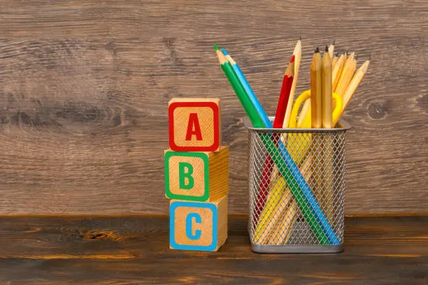 ABC letters painted on wooden blocks and colorful pencils in basket