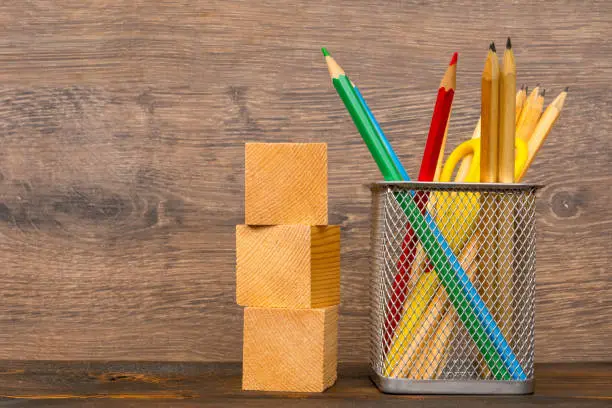 wooden blocks and colorful pencils in basket on wooden table