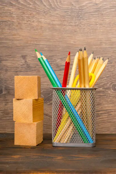 wooden blocks and colorful pencils in basket on wooden table