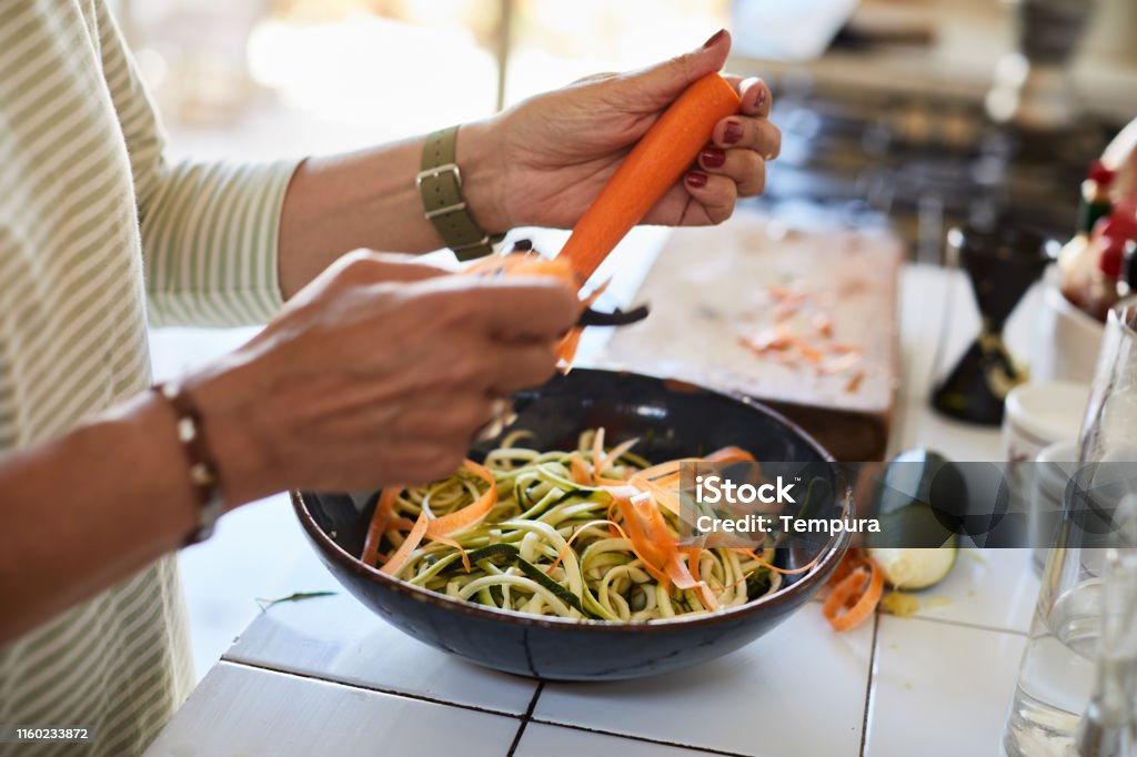 Vegan food, close-up of hands pealing a carrot, making a salad. Lifestyle vegan diner Vegetable Stock Photo
