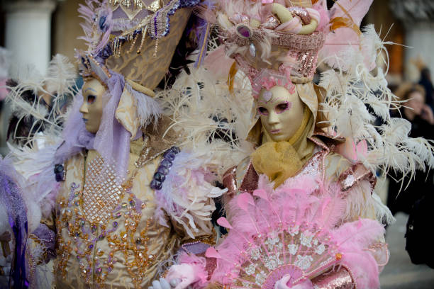 Venice, Veneto, italy - 6 february 2016: Individual in ornate Venetian masquerade attire wears an elaborately designed mask adorned with gold and pink details.