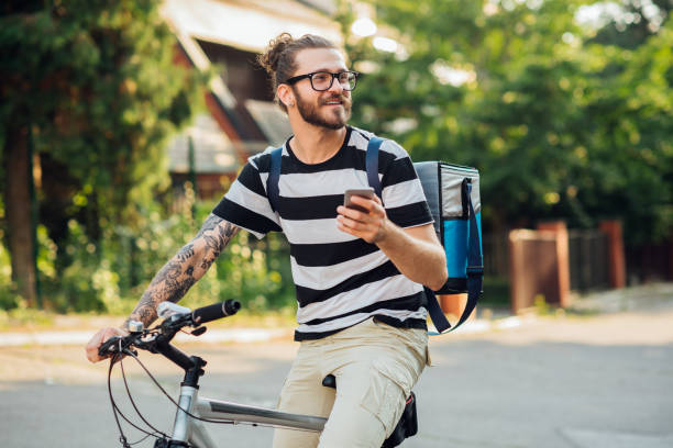 Man cycling and texting Handsome man on a bike using smartphone searching around hipster bike stock pictures, royalty-free photos & images