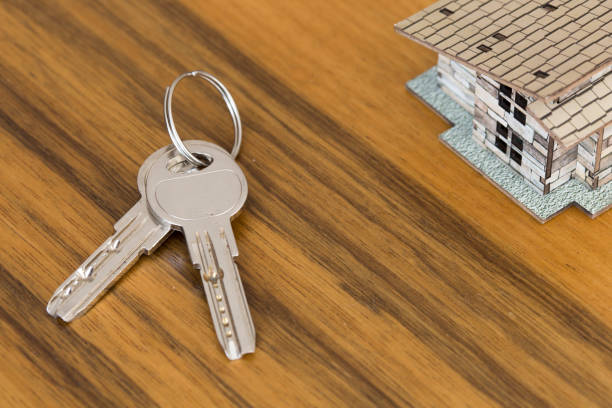 Home key with house keyring on black wood table in dark tone, copy space, real estate concept