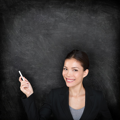 Teacher woman. Female teaching or college university student at blackboard in business suit. Young female mixed race Asian Caucasian female student.