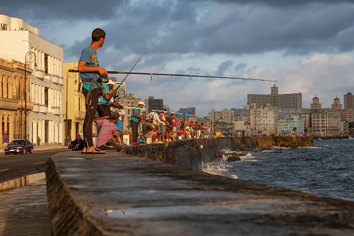 Havana, Cuba - May 25, 2019: Cuban people are fishing in the ocean early morning during a sunny and cloudy sunrise, taken during the Shortage of Food Crisis.