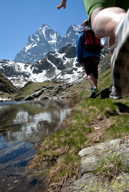 istock Hikers walk along path at edge of mtn lake 116025714