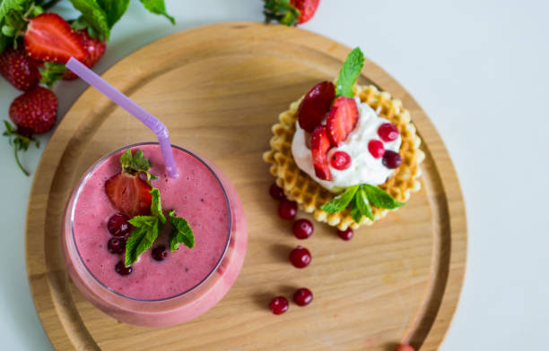 colazione mattutina con smothie alla fragola e cialde con panna montata e bacche - healthy lifestyle cranberry healthy eating milk shake foto e immagini stock