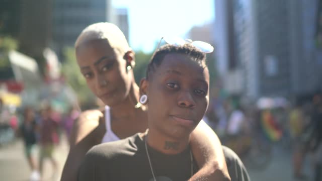 Portrait of lesbian couple looking at camera during pride parade