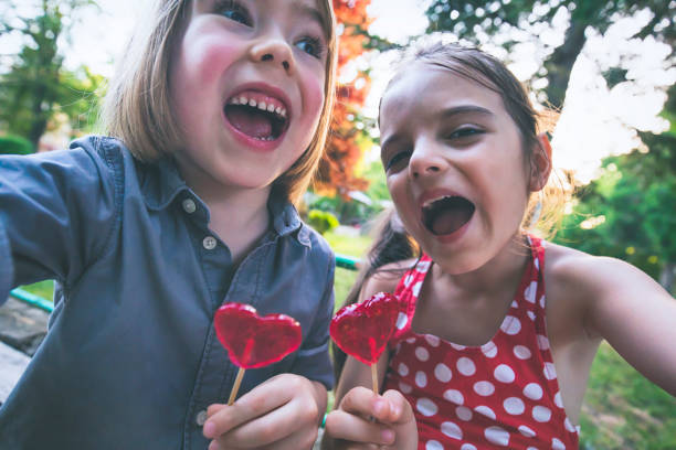 楽しみを持って、自分撮りを作るロリポップを持つ子供たち - child valentines day candy eating ストックフォトと画像