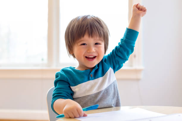 Happy toddler raising his hand stock photo