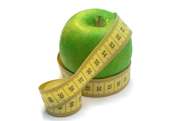 istock Green apple wrapped by measuring tape isolated on white background 1160272792