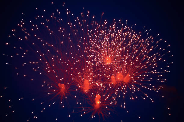 istock Inexpensive bright sparkling fireworks, red, with haze, in the night sky 1160275578