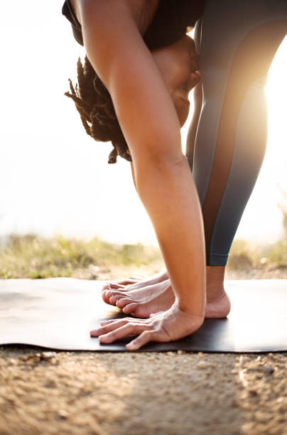 Finding fitness balance Shot of a fit young female exercising yoga outdoors in nature touching toes stock pictures, royalty-free photos & images